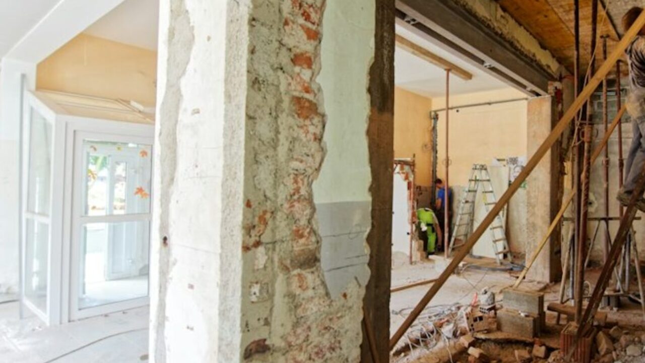 Concept visual: a house interior during renovation, with stripped plaster and exposed structure.