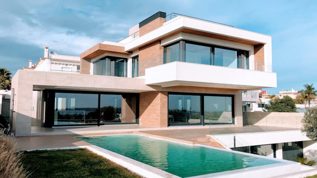 Concept visual: a luxury villa with a deck, pool and warm stone façade.