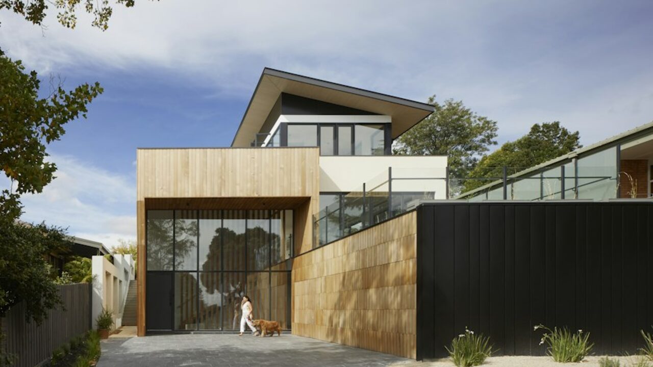 Modern house exterior with a rendered boundary wall, gate and paved approach.